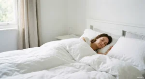 Person sleeping peacefully on white bed with natural morning light